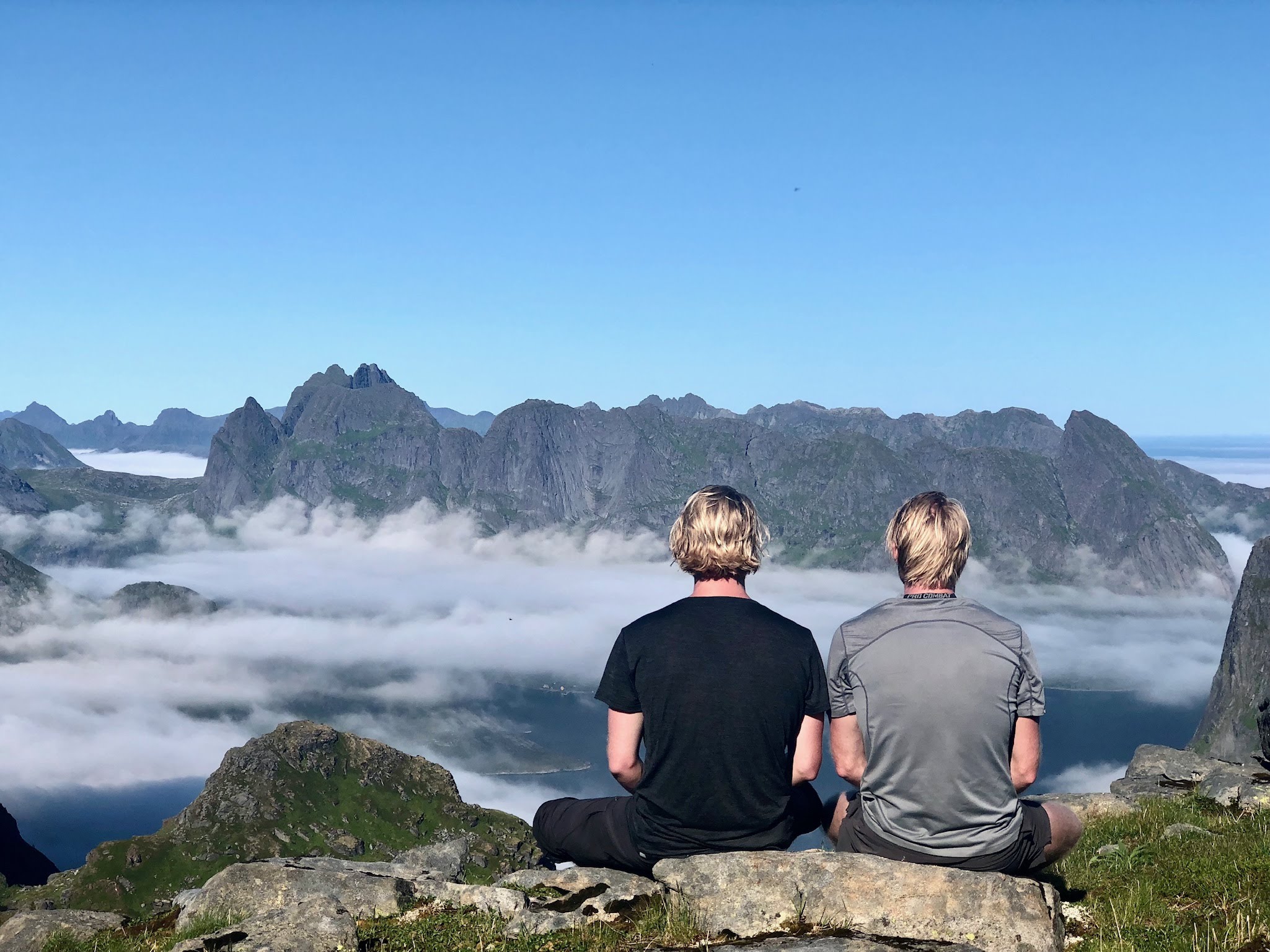 två män mediterar på ett berg med ryggen mot kameran