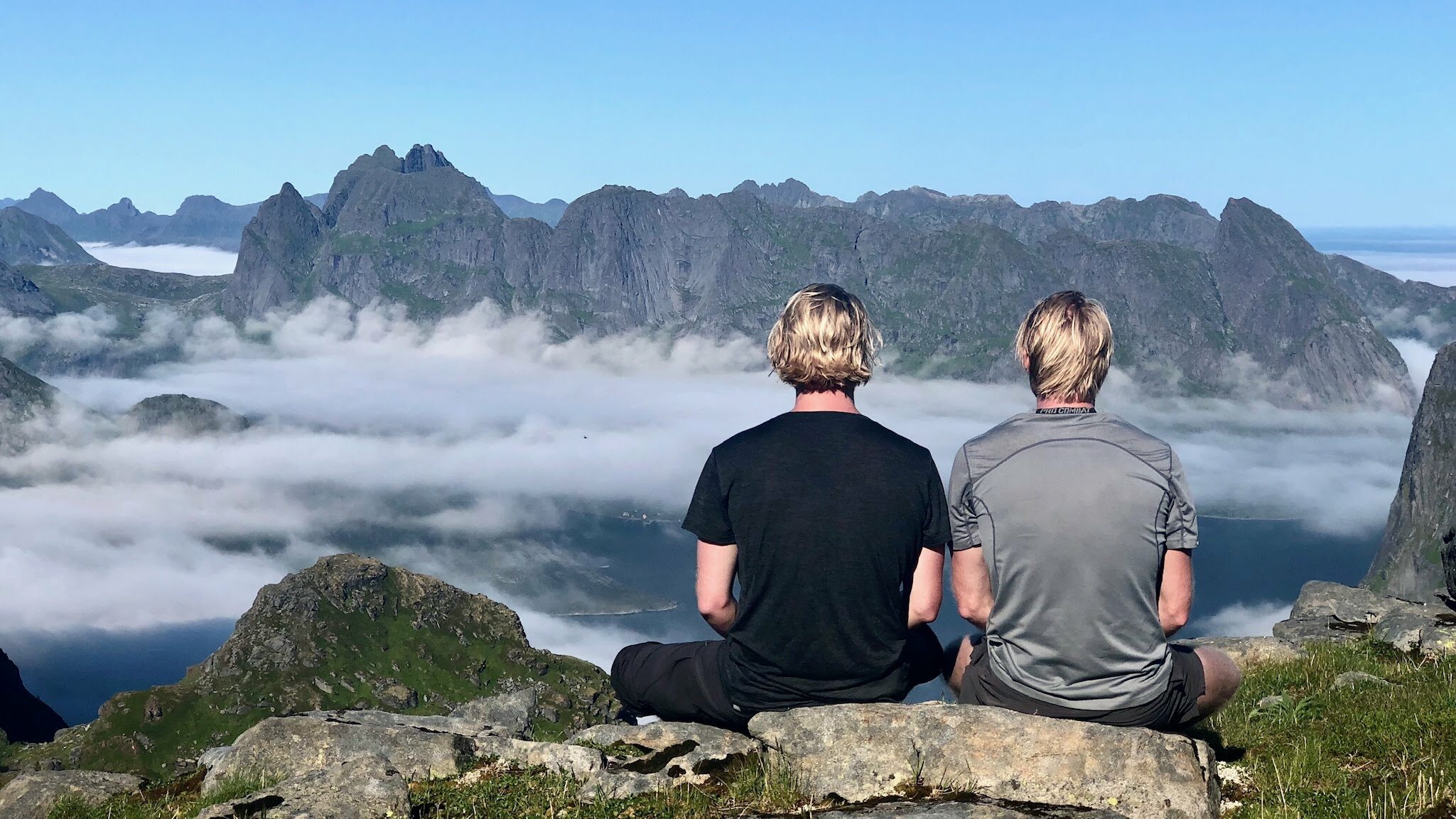 två män mediterar på ett berg med ryggen mot kameran